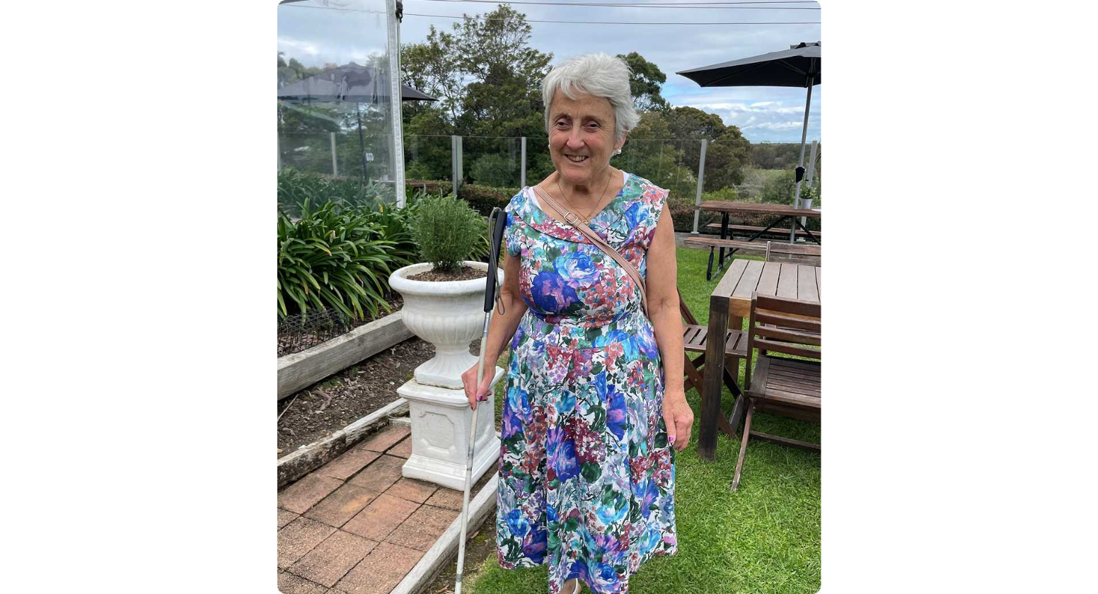 Debbie with her white cane in the garden.