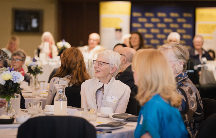 A lady sitting at an event table, listening attentively