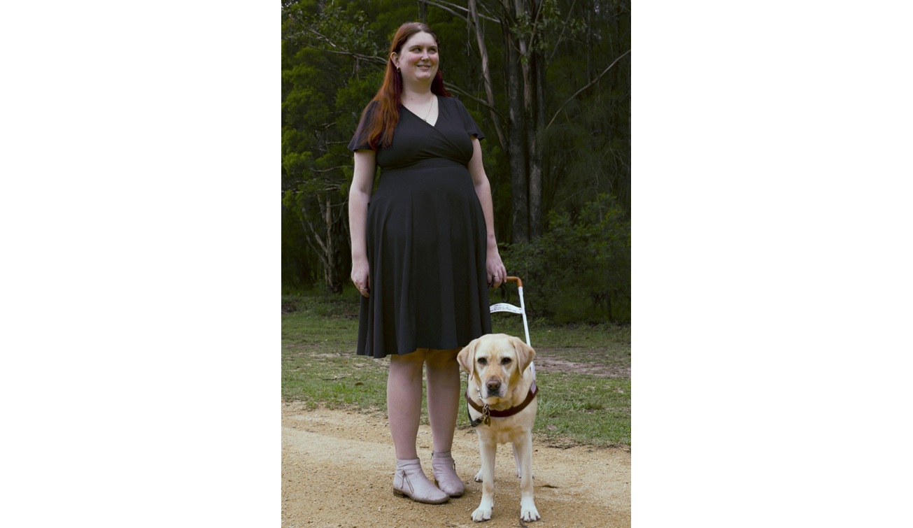 Kirsten stand outside, Kimba a yellow Labrador Seeing Eye Dog stands next to her.