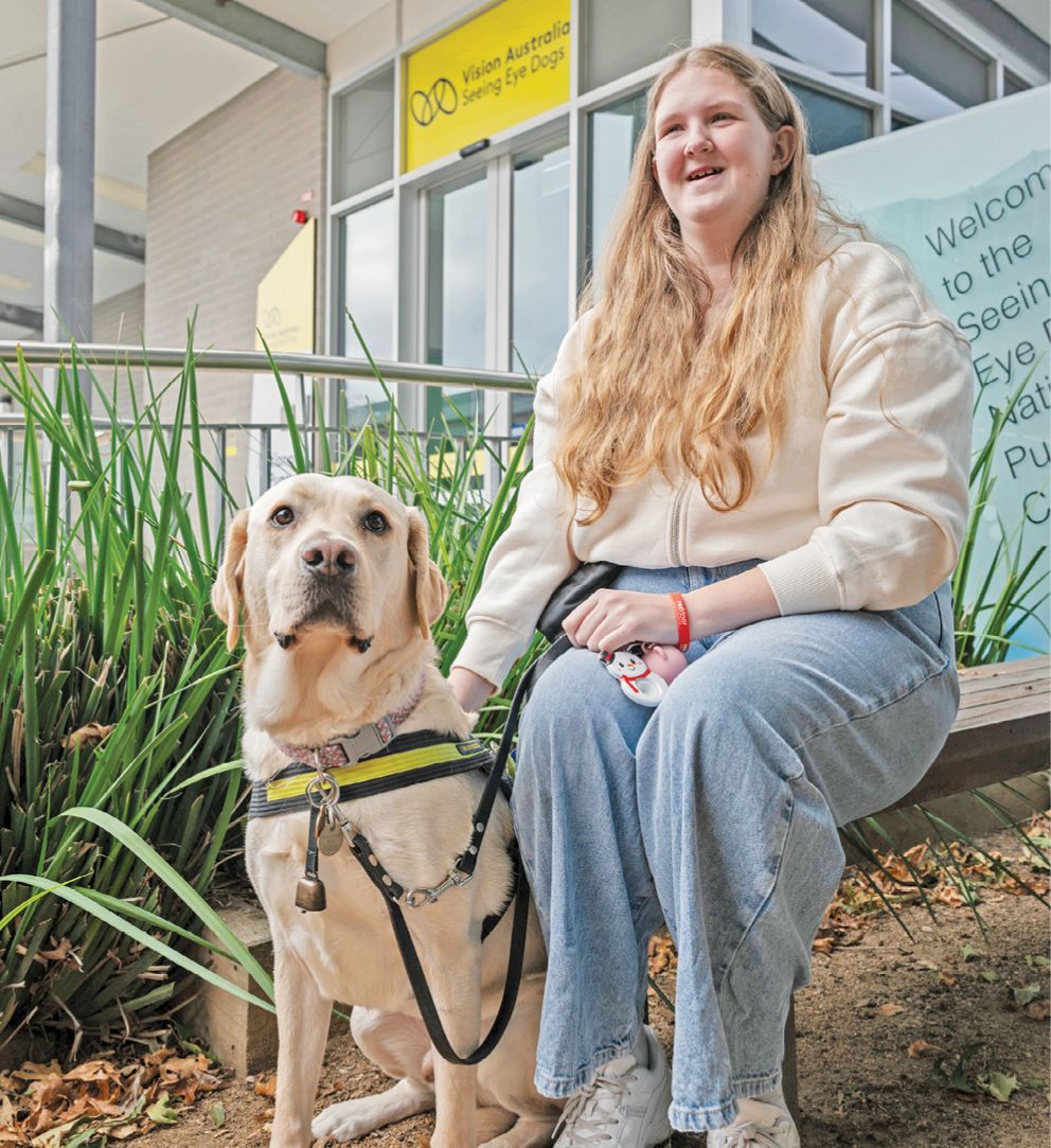 Jasmine sitting with her yellow Seeing Eye Dog.