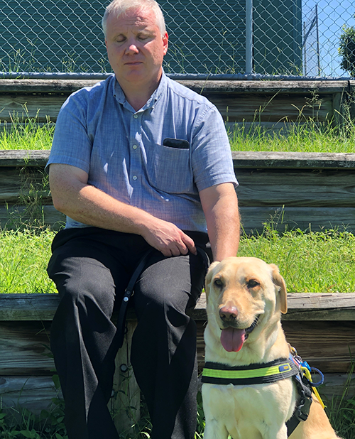 Damo sits beside Seeing Eye Dog, Ebony