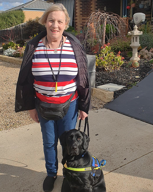 Denise stands next to her Seeing Eye Dog in harness