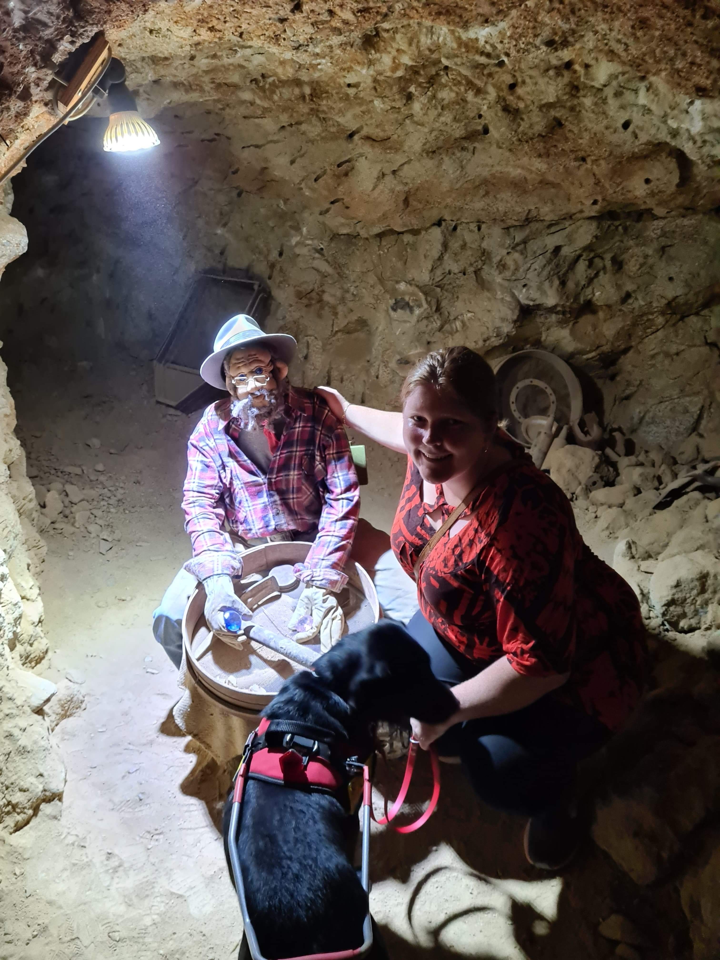 "Isabella being guided through a gem cave with Seeing Eye Dog Penny by her side."