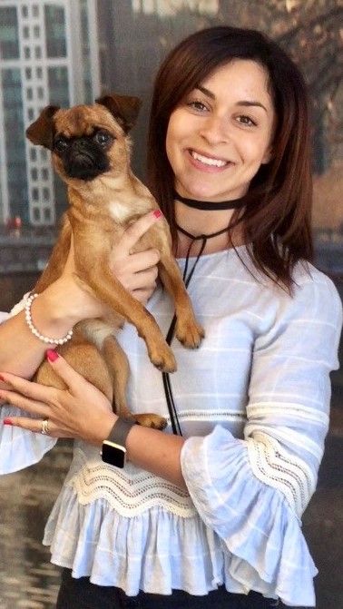 Mina Hamilton smiling at camera and holding a small dog
