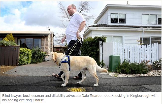 Dale Reardon walks with Seeing Eye Dog, caption text: Blind lawyer, businessman and disability advocate Dale Reardon doorknocking in Kingborough with his seeing eye dog Charlie.