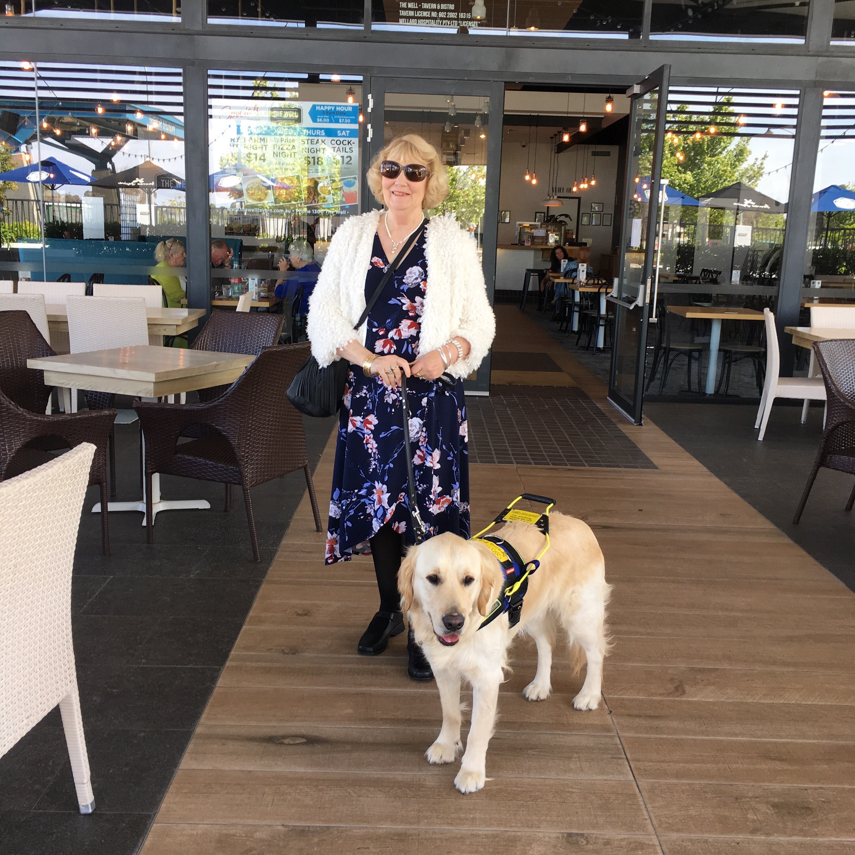 Therese stands with Seeing Eye Dog Yael outside a cafe.