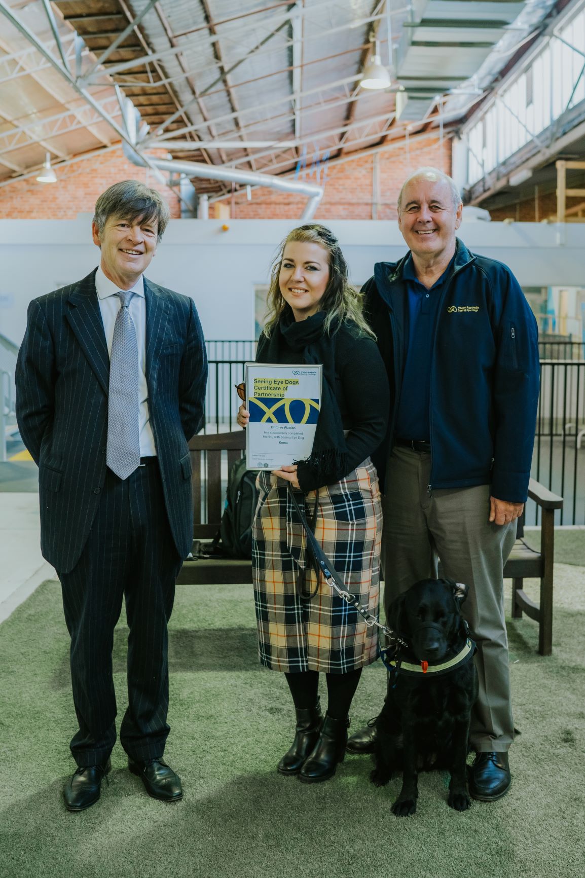 L TO R: The Hon. Luke Donnellan, Minister for Child Protection, Disability, Ageing and Carers, Seeing Eye Dogs client Britnee holding her certificate, Vision Australia CEO Ron Hooton, SED Kuma