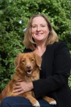 Professor Claire Wade sitting outside with a dog on her knee